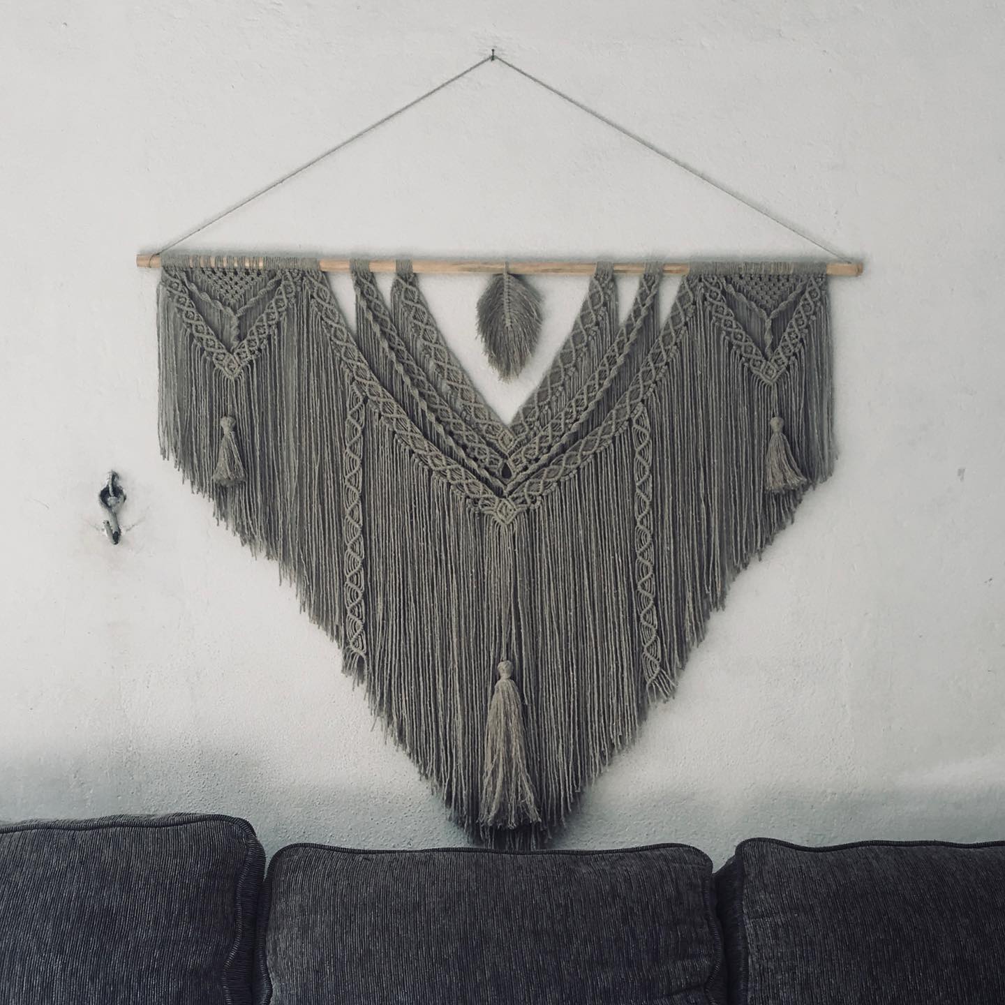 Grey triangular wall piece with feather pendant